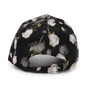 Détail de la boucle en métal ajustable et du motif de rose blanche sur casquette noire