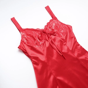 Detail of red satin dress featuring intricate floral lace stitching and a delicate bow