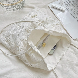 Vue de dessus montrant l'intérieur spacieux et la poche zippée du sac fourre-tout en dentelle