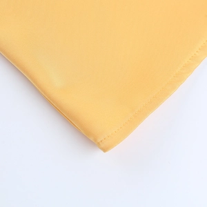 Détail de la texture satinée jaune et coutures de qualité sur la robe dos nu licou