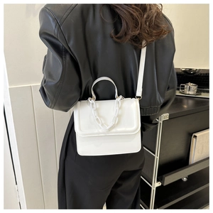 Close-up of white minimalist square crossbody bag with matching white chain decoration