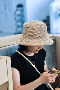 Close-up of hand-woven raffia texture on a flat-top sun hat with natural straw fibers