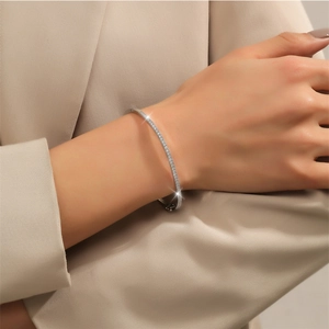 Detail eines minimalistischen Silberarmreifs mit Zirkonia-Besatz am Handgelenk getragen
