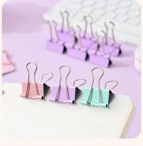 Close-up of macaron colored binder clips attached to a notebook for office organization