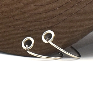 Close-up of brown twill baseball cap brim featuring two silver metal rings decoration