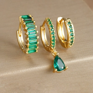 Macro view of gold-plated geometric earring set featuring emerald green drop crystals