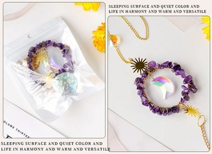 Detail of purple crystal suncatcher with golden moon and sun pendants on white background