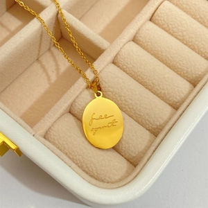 Macro detail of gold oval pendant featuring free spirit engraving on delicate O-chain