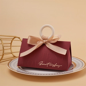 Detail of burgundy wedding favor box with champagne ribbon and wooden ring handle
