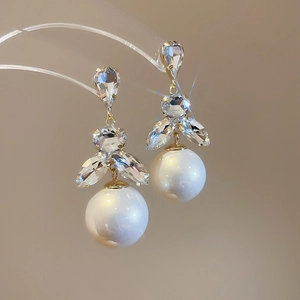 Detail of warm gold tassel earrings with marquise rhinestones and elegant white pearls