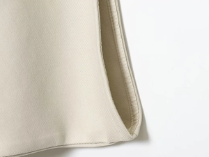 Detailed close-up showing beige twill fabric texture and neat stitching on the garment