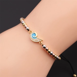 Close-up of tricolor beaded bracelet with blue enamel zircon charm on a braided cord