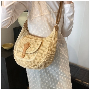 Detail of hand-woven straw shoulder bag with brown leather buckle and rivet accents