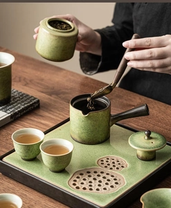 Detail shot of green glaze ceramic tea set with side-handle teapot on a wooden tray
