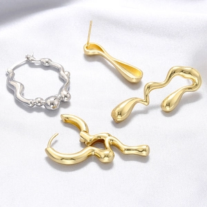 Detailed macro view of gold and silver irregular fluid metallic stud earrings on white silk