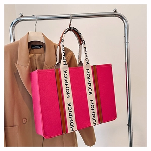 Pink felt tote bag with MOMPICK lettered straps hanging on a khaki suit background