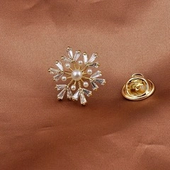 Macro view of gold snowflake brooch featuring white pearls and crystal inlay detail
