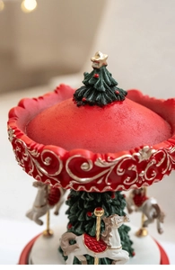 Macro detail of Christmas carousel music box with golden scrolls and resin tree