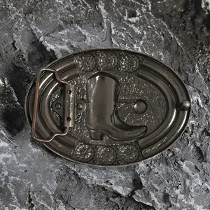 Vintage western cowboy belt buckle with embossed boots and floral patterns on stone background