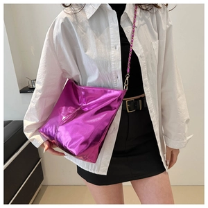 Close-up of pink metallic bucket bag with chain strap worn by model in casual outfit