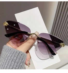 Detail view of purple gradient lens with golden metal leopard head emblem on rimless sunglasses