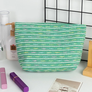Close-up of woven cosmetic bag with green white stripes and colorful polka dots