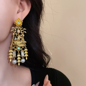 Macro detail of vintage gold floral bird earrings with faux pearls and rhinestones