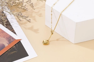 Detail of a gold heart pendant with sunburst engraving on a unique mixed link chain