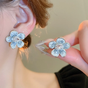 Detailed view of blue crystal flower earrings featuring a central white stone and silver posts