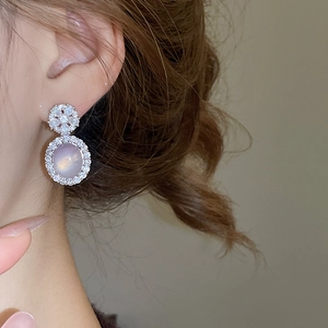 Détail de boucles d'oreilles en zircon avec calcédoine ovale et motif fleur en gros plan
