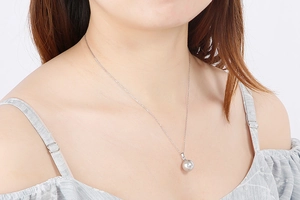 Close-up of a silver titanium necklace with a shell pearl pendant worn by a model