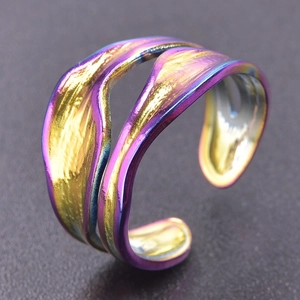 Macro shot of iridescent gradient snake-shaped stainless steel wave ring with polished finish