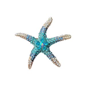 Vintage gold starfish brooch with blue and white crystals on a white background