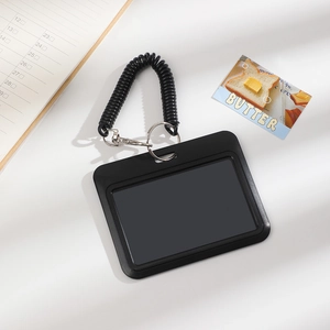 Detail of black card holder with spiral spring coil and metal lobster clasp on white surface