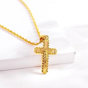 Detailed close-up of a gold-plated crucifix pendant with intricate Jesus carving and rope chain