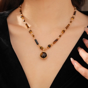 Close-up of beaded necklace with tiger eye stone pendant on model neck