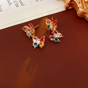 Detailed macro view of colorful zircon butterfly earrings on vintage leather background