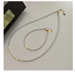 Dettaglio del set collana e bracciale di perle con accenti dorati e chiusura a moschettone