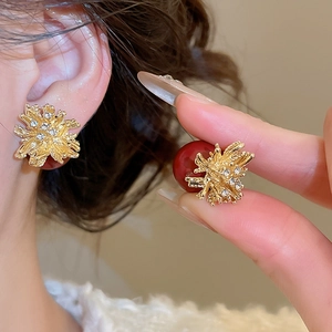 Macro shot of gold firework flower earrings with rhinestones and large red bead detail