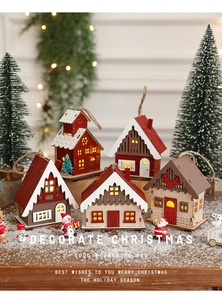 Close-up of lighted miniature wooden Christmas houses with warm LED glow on snowy surface