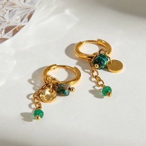 Detailed macro view of gold hammered hoop earrings with green natural stone beads