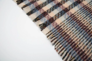 Detail shot of multicolor plaid scarf featuring fine twill weave and frayed tassel edges