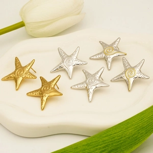 Elegant starfish stud earrings in gold and silver finish on a white ceramic tray