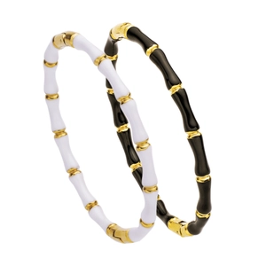 Detail view of bamboo-shaped bracelets in gold with black and white enamel sections