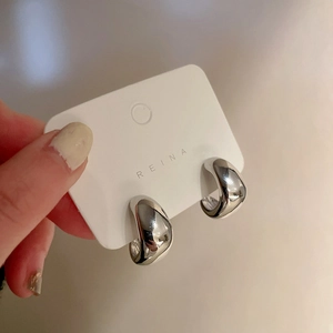 Detailed macro view of minimalist silver C-shaped thick hoop earrings on a display card