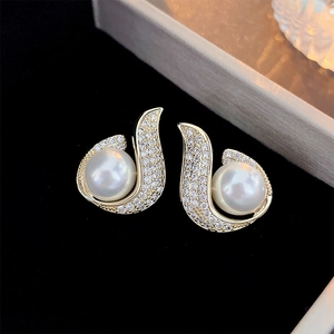 Macro shot of gold-plated mermaid fishtail earrings with sparkling zircon and pearl inlay