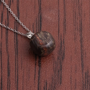 Detailed view of round dark stone pendant with red-brown veins on a silver metal chain