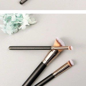 Close-up of foundation and concealer brushes with black handles and gold ferrules