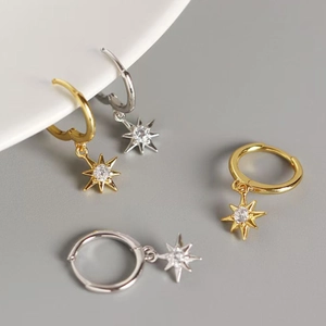 Detailed close-up of gold and silver star hoop earrings with white zircon inlays