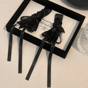 Detail view of handmade black ribbon hair clips with elegant 3D satin roses and streamers
